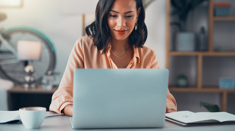 A woman with dark hair typing on a laptop