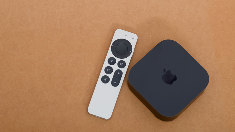 an Apple TV device with an Apple TV Remote next to it, orange background