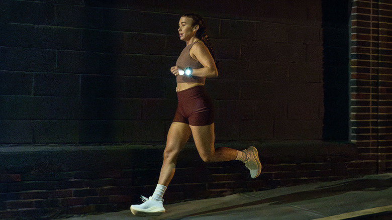 A woman running in the dark while wearing the Garmin Forerunner 970 that's lit up.