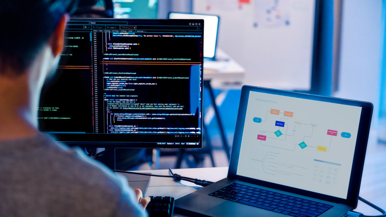 Software engineer working on a laptop and second screen monitor