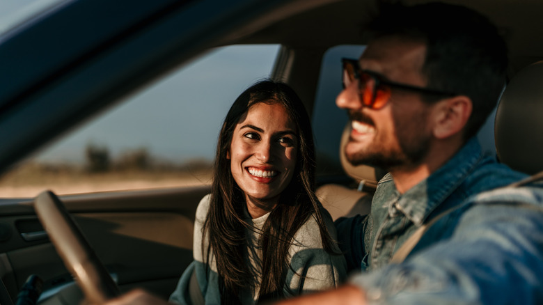 man and woman laughing as they drive in car