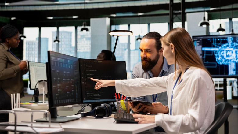 Software developers collaborating on lines of code on a computer screen.