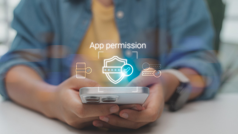 Hands holding phone with app permission graphic