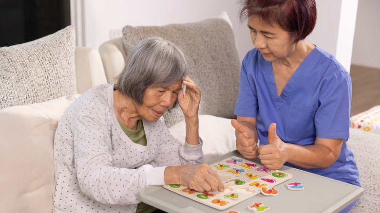 a nurse helps an Alzheimer's patient with a number puzzle