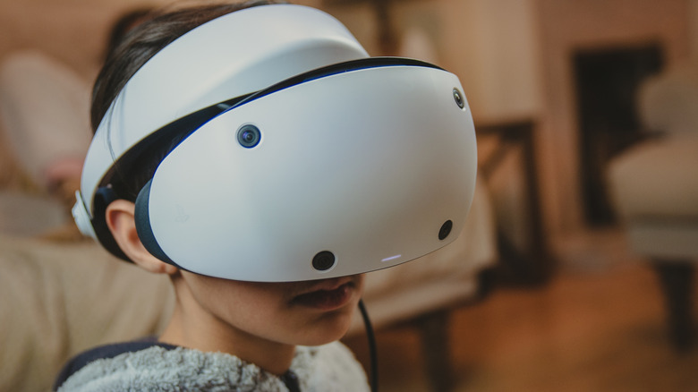 Person wearing a PlayStation VR2 headset indoors.