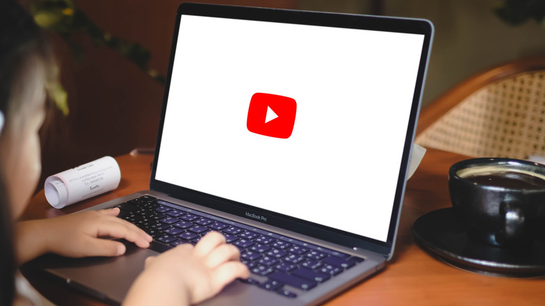 Hands on laptop keyboard with YouTube logo on the screen