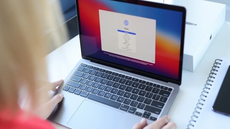 A woman selecting the system language on an Apple MacBook Air