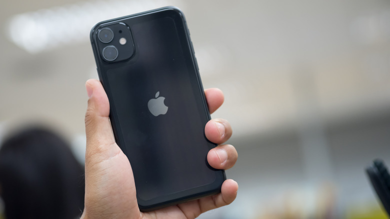 Close-up of a person's hand holding the iPhone 11 in black
