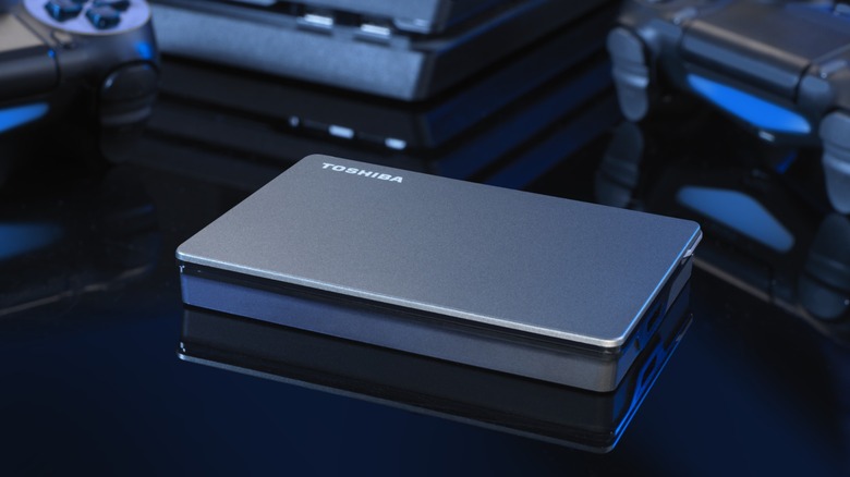Toshiba Canvio Gamin external hard drive surrounded by PlayStation 4 and DualShock 4 controllers