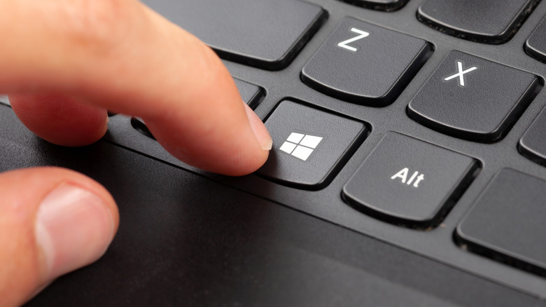 A finger pressing the Windows key on a keyboard