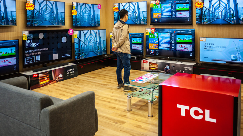 A man looking at TCL TVs in a display area.