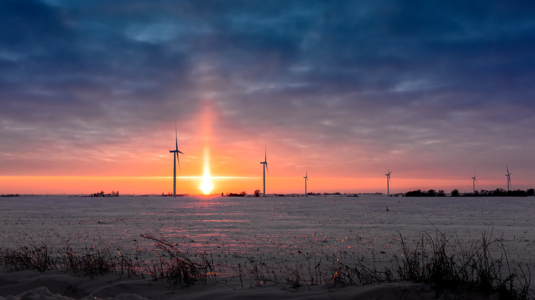 Wind turbines against a sunset on an Iowa field in the winter