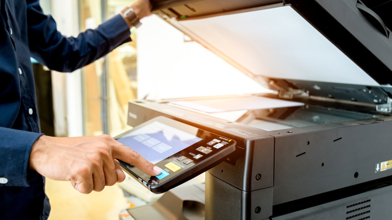 A person using a large, office-style printer/copier.