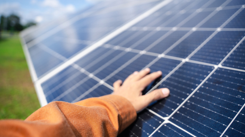 A person touches the surface of a monocrystalline solar panel.