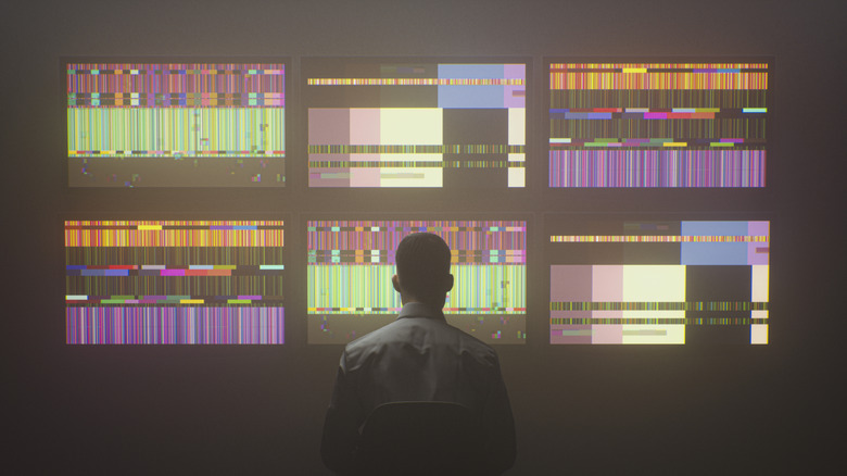man sitting in front of multiple TV screens, concept of man watching multiple TVs at the same time