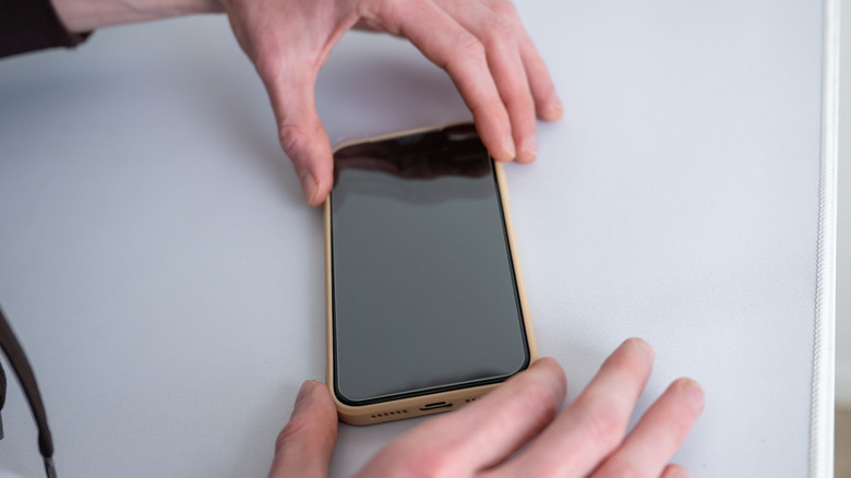 Hands placing screen protector on a phone