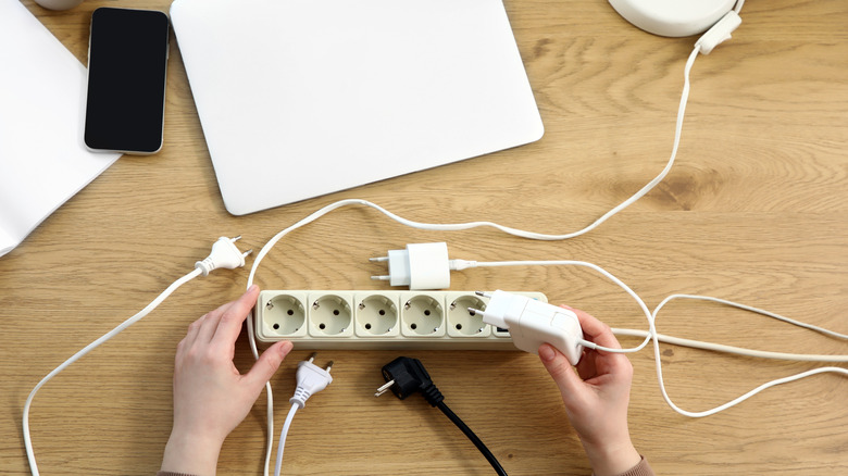 hands unplugging a charger from a power strip