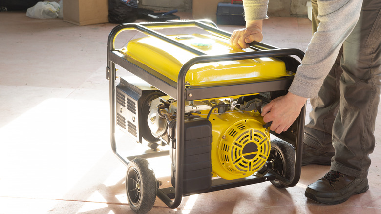 A person starting a portable gas generator.