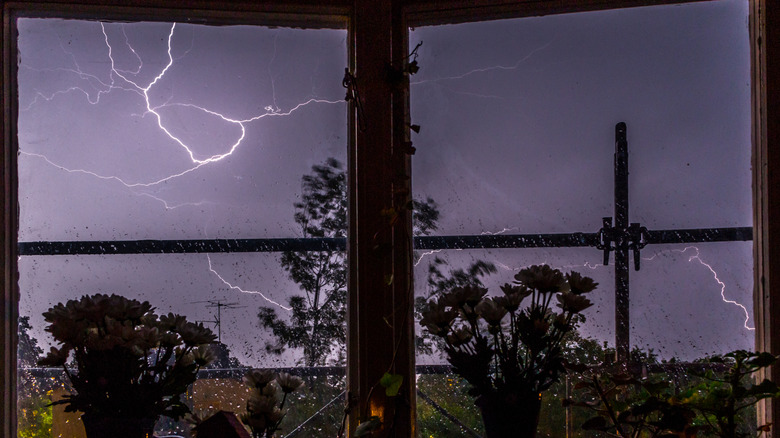 lightning striking during a thunderstorm is visible through a window