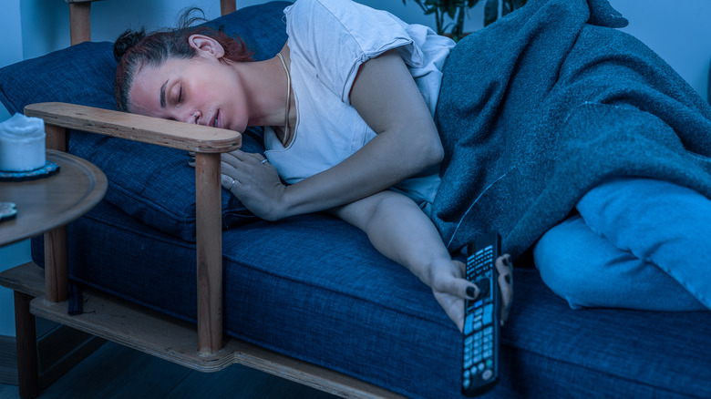 woman is asleep with a TV remote in her hand