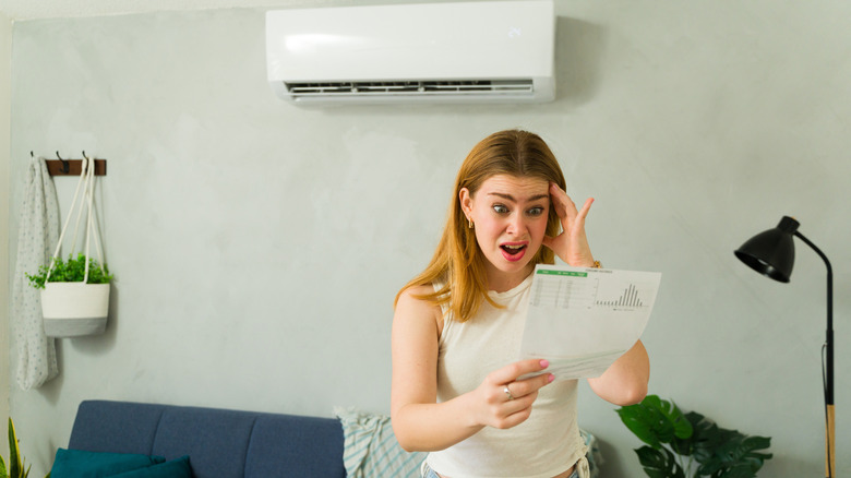 a woman is shocked by the cost of her electricity bill