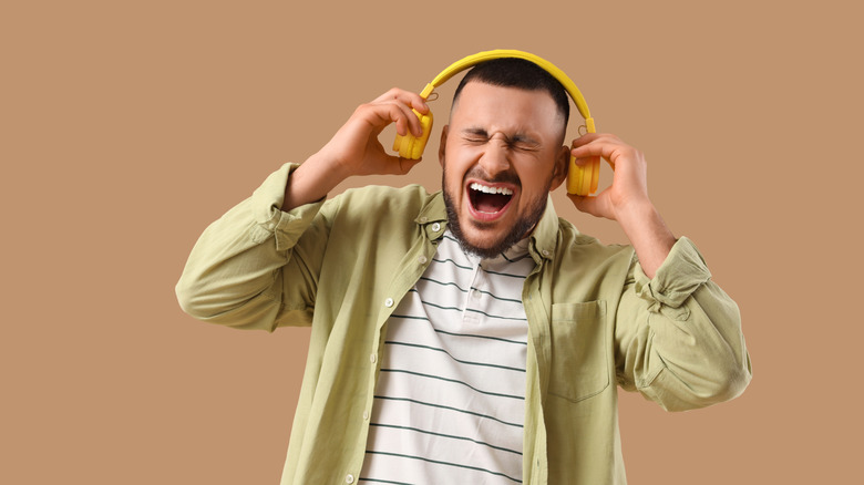 A man holding headphones away from ears