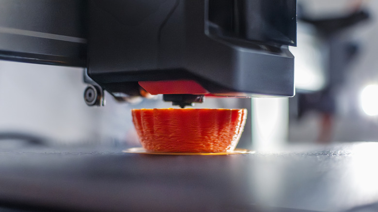Close up of an item being 3D printed with orange filament.