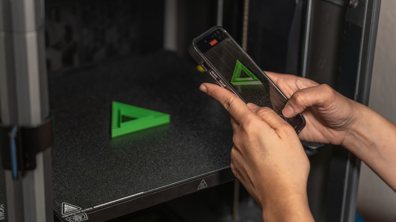 Someone taking a photo of a 3D print inside an enclosed printer.