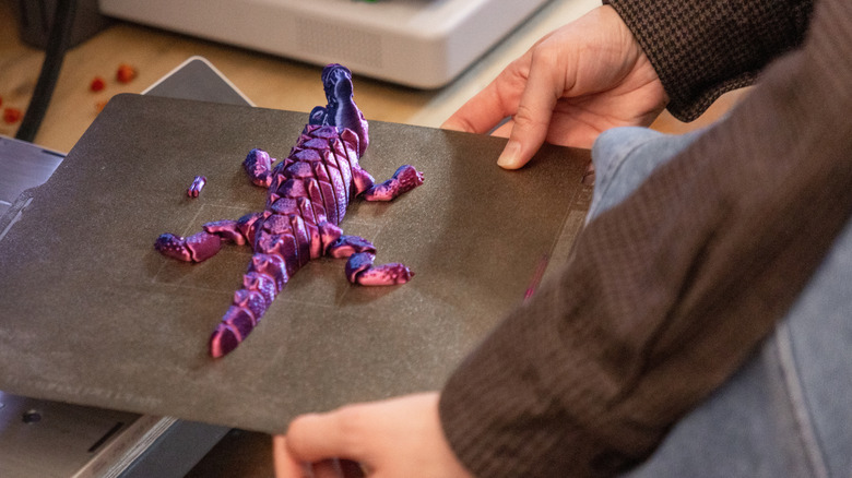 Multi-colored 3D printed reptile stuck to a printer bed.