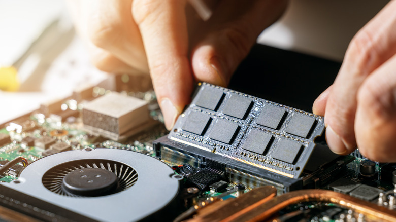 A close up of hands installing RAM on a computer