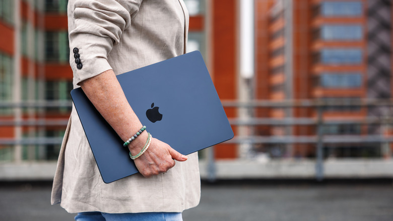 A person walking with the MacBook Air in hand