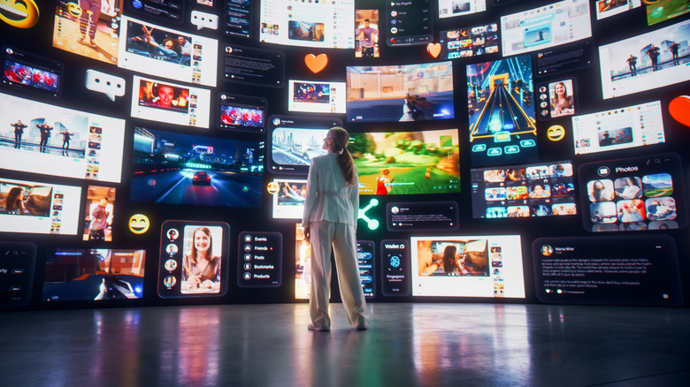Women standing infront of a group of TVs showing different programming