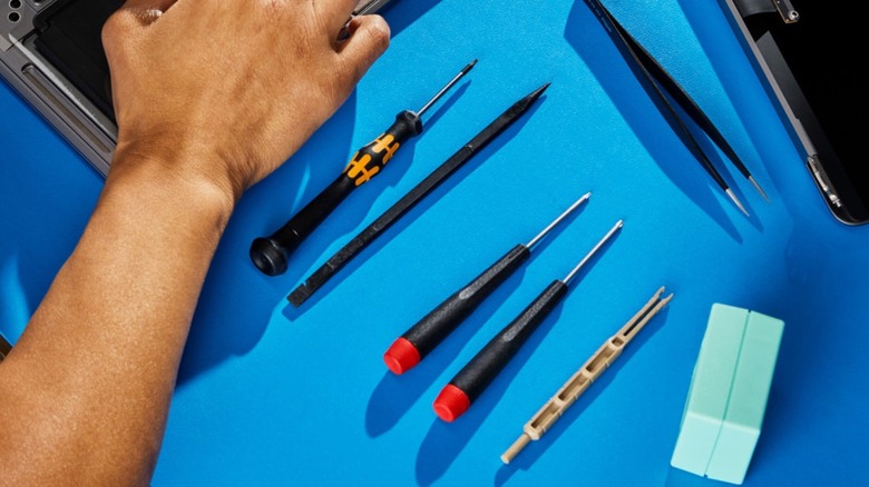 Close up of a hand and tools to fix a MacBook