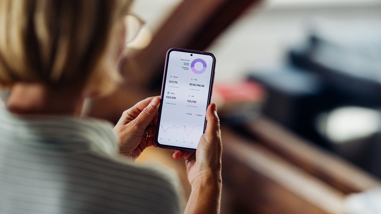 A woman using a financial app on an iPhone