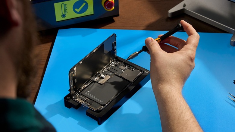 A man removing the screws from an open iPhone