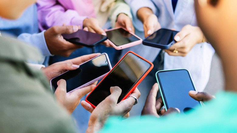 A group of people holding their phones in a circle