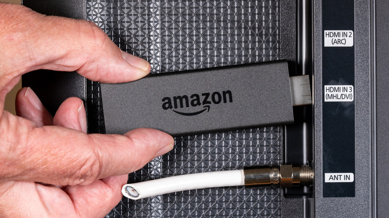 A person plugging in an Amazon firestick into HDMI port
