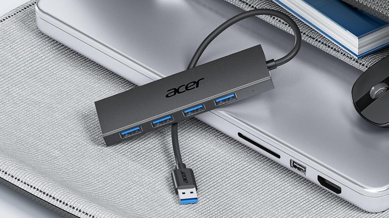 An unplugged Acer USB Hub on top of an Apple laptop and carrying case