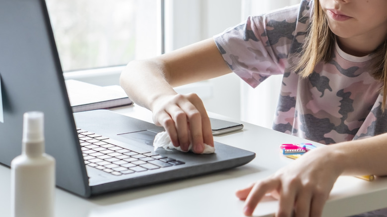 Hands cleaning laptop on table