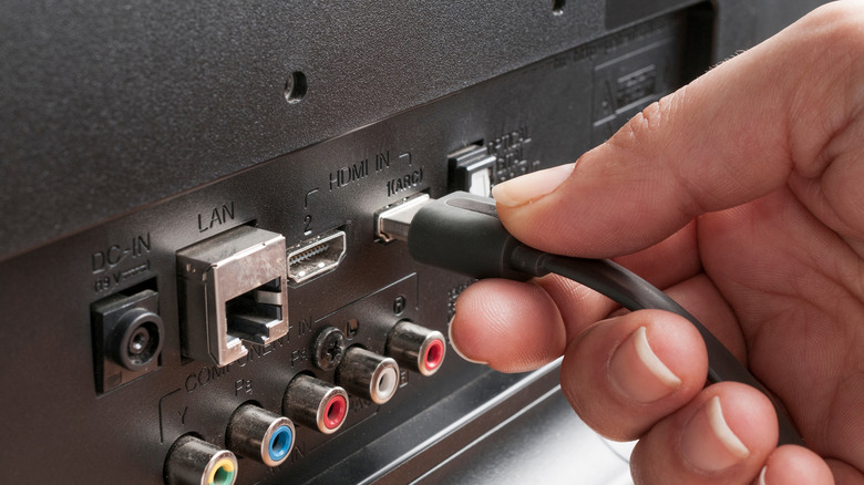 A person plugging an HDMI cable in a TV