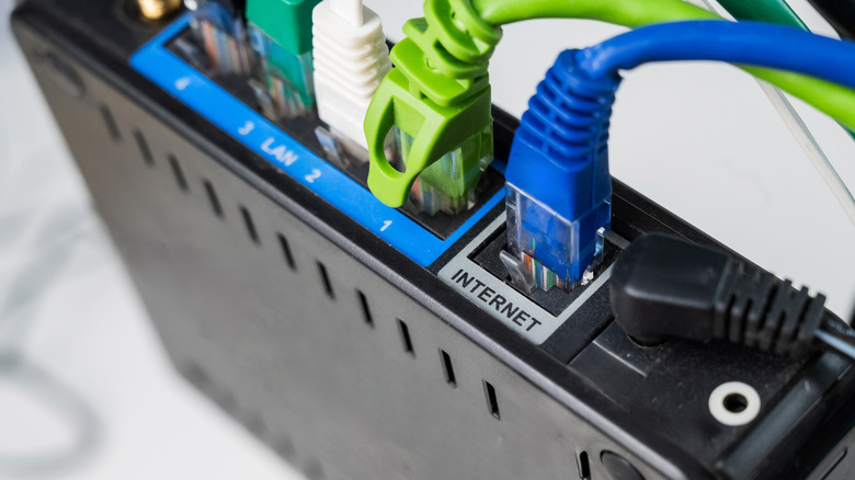 Various Ethernet cables plugged into the back of a router with limited ports.