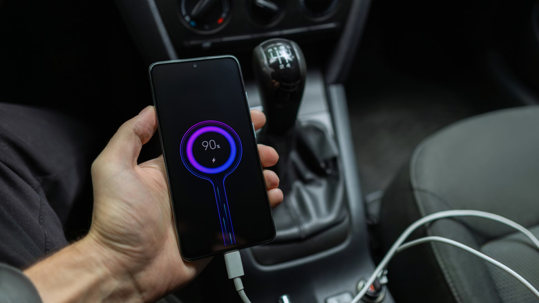Hand holding phone while charging in the car
