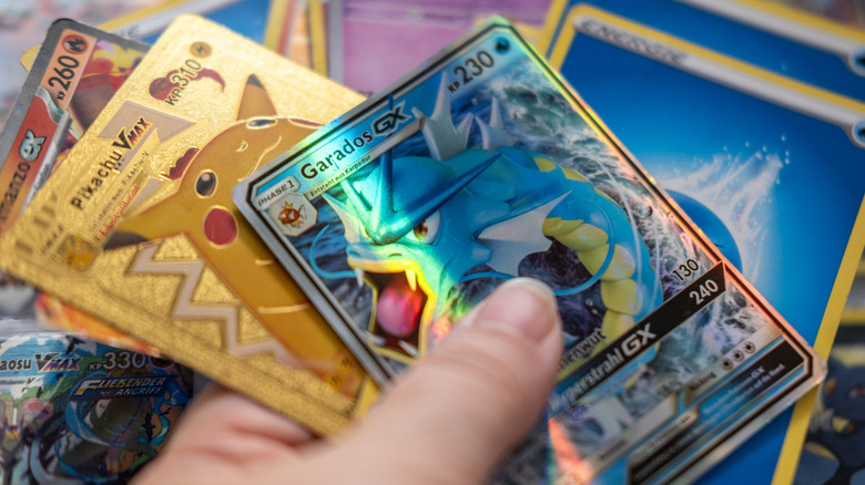 A hand holding several Pokémon trading cards.