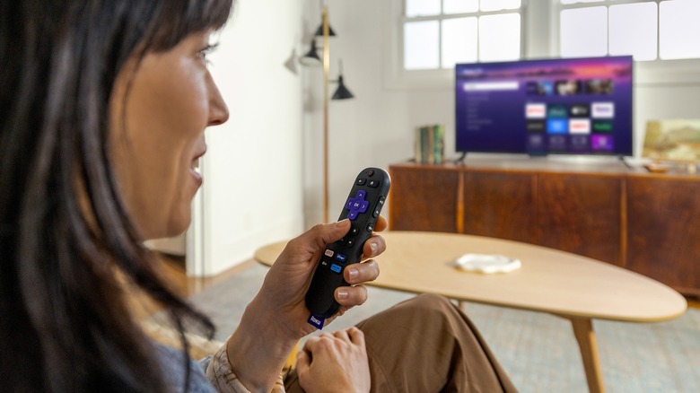 A person using a Roku remote in their living room to control a TV