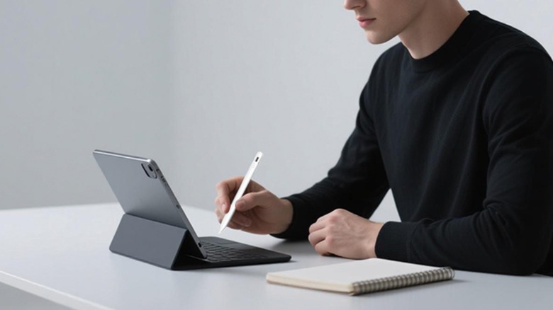 A promotional image for the AMZ Fire Tablet Style pen, an individual in a black shirt sits in an all white room, their left hand using the white stylus pen on a black tablet with keyboard accessory