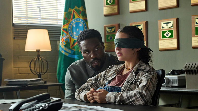 John Creasy talks to a blindfolded Poe in what looks like the Brazilian embassy.