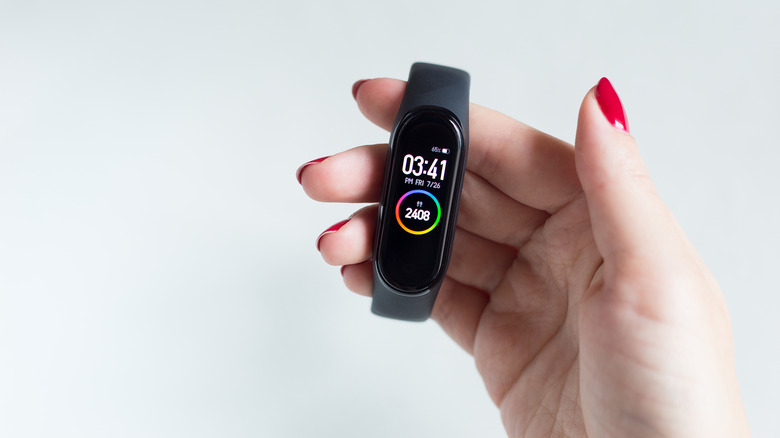 a woman's hand holding up a Xiaomi Smart band