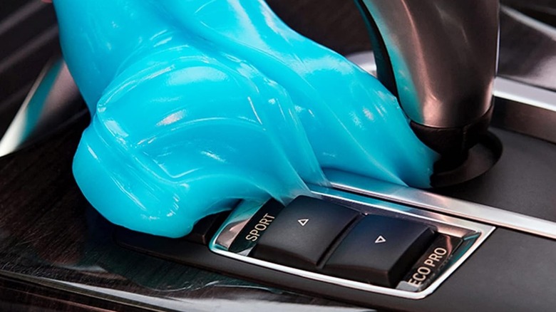An Amazon promotional photo for the PULIDIKI Car Cleaning Putty, the image shows the blue putty on next to the shift knob within a vehicle