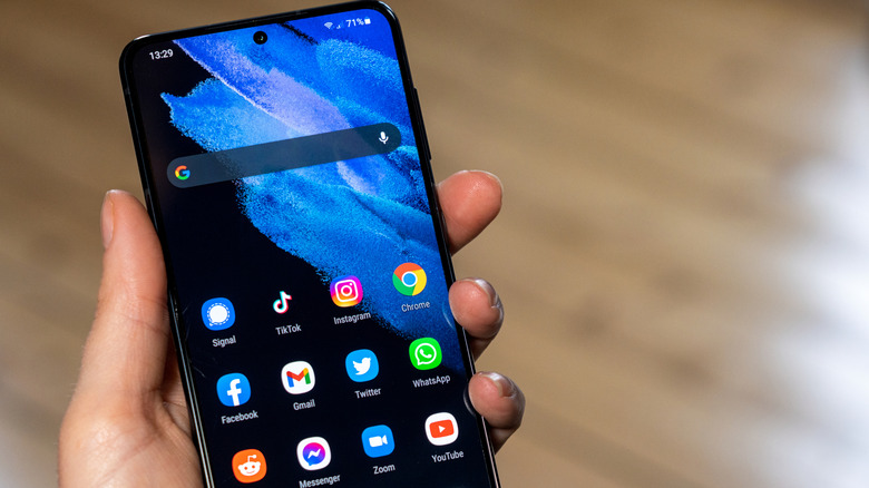 Person holding an Android device in their hand while on the homescreen