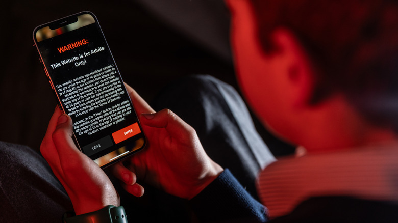 Person using smartphone displaying a warning for age verification
